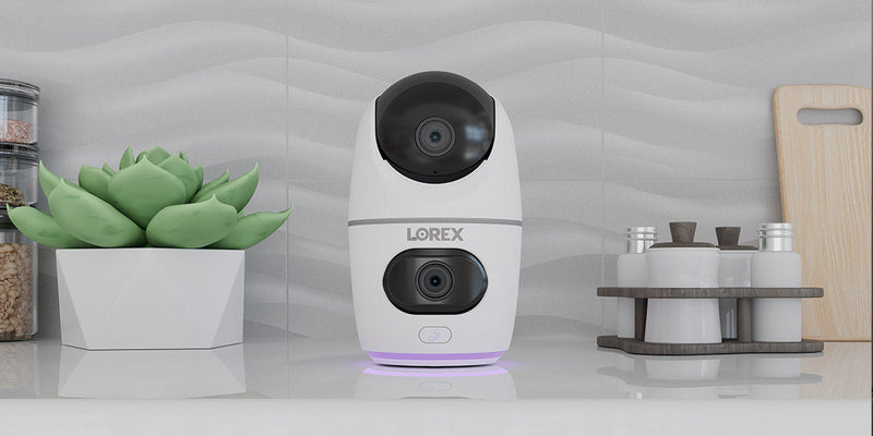 Lorex W463 2K dual-lens indoor pan-tilt Wi-Fi security camera on a kitchen countertop.